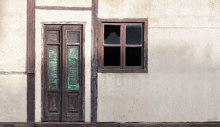 old house wall with wooden door and windowの写真素材