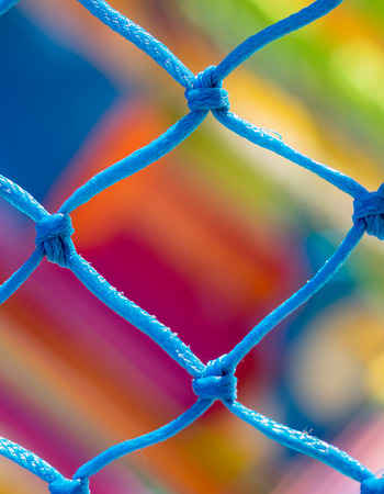 Blue net close up and very colorful background in children playgroundの写真素材