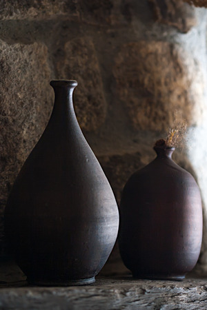 Two ceramic vases against rustic wooden wall.の写真素材