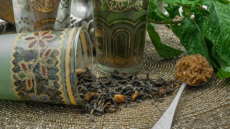Black tea in a crystal glass, mint leaves, dried tea, brown sugar and cinnamon .の写真素材