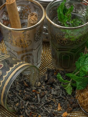 Black tea in a crystal glass, mint leaves, dried tea, brown sugar and cinnamon .の写真素材