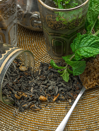 Black tea in a crystal glass mint leaves dried tea brown sugar and cinnamon .の写真素材