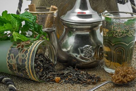 Black tea in a crystal glass mint leaves dried tea brown sugar and cinnamon .の写真素材