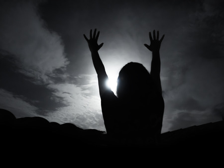 Silhouette of woman against full moon with hands upの写真素材