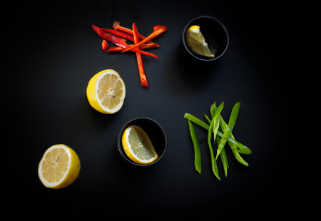 Red and green peppers and lemon. Low key natural lightingの写真素材