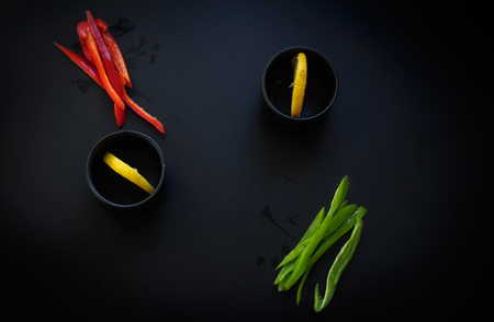 Red and green peppers and lemon. Low key natural lightingの写真素材