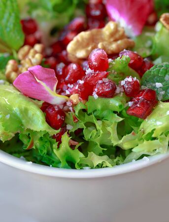 Close up of curly endive salad with pomegranate, nuts, rose petals, peppermint, olive oil, balsamic vinegar and saltの写真素材