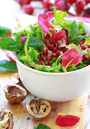 Curly endive salad with pomegranate, nuts, rose petals, peppermint, olive oil, balsamic vinegar and saltの写真素材