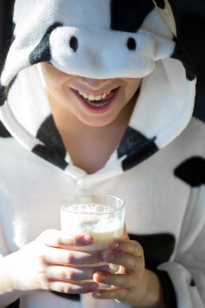 Portrait of child with cow pajamas, holding a glass of milkの写真素材