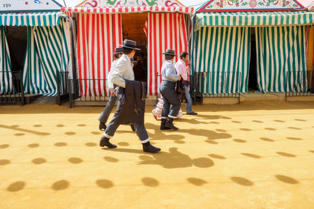 Seville, Spain - April 23, 2015: Riders walk through the April Fair Seville dressed in tradional "traje corto" with casetas behind. The Seville Fair "Feria de abril de Sevilla" is one of most important celebration of the city, it begins one or two week afのeditorial素材