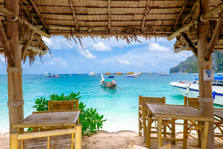 Thai restaurant on a tropical beach with wooden tables and straw umbrellas. Phi-Phi island, Krabi Province, Thailand.の写真素材