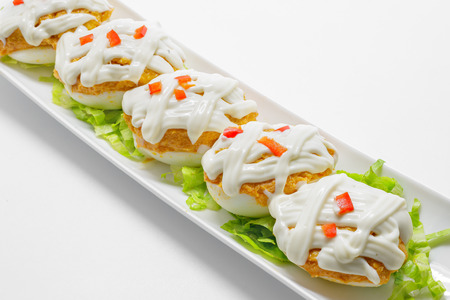 Stuffed eggs with tuna, tomato, mayonnaise and red pepper on white backgroundの写真素材