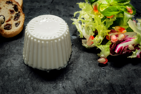 Close up of Fresh cheese with salad of fresh vegetables and pomegranate on dark slate stoneの写真素材