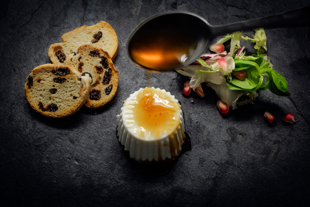Fresh cheese and Honey with salad of fresh vegetables and pomegranate on dark slate stoneの写真素材