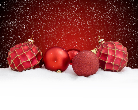 Christmas balls on snow over red background. Merry christmas card with falling snowの写真素材