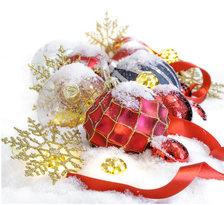 Christmas ornaments  in the snow with red ribbonの写真素材