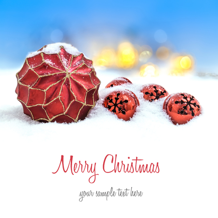 Red Christmas ornaments in the snow and defocused lightsの写真素材