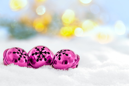 Christmas jingle bells on snowy background and defocused lightsの写真素材