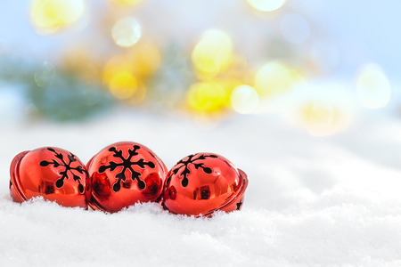 Christmas jingle bells on snowy background and defocused lightsの写真素材