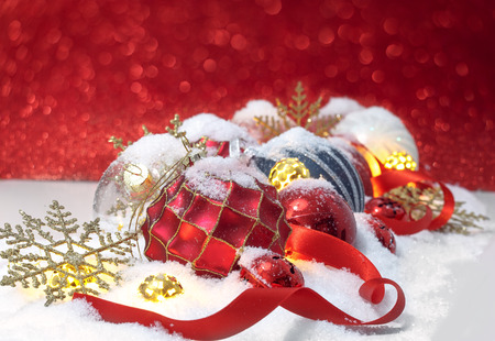 Christmas ornaments  in the snow over red backgroundの写真素材