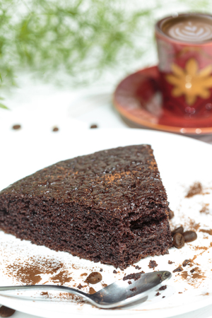 Chocolate cake on the white plate with a cup of coffeeの写真素材