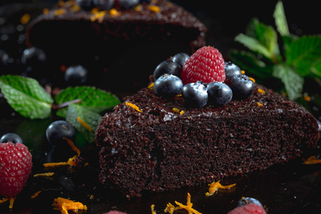 Piece of dark chocolate cake decorated with raspberries.