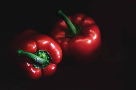 Two red bell peppers on dark background.の写真素材