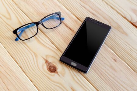 Smartphone and glasses mockup on a wooden tableの写真素材