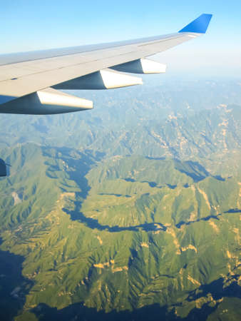 Wing of an airplane flying above mountains. Traveling concept. Photo applied to tourism operators.の写真素材