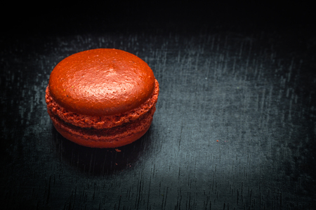 Sweet red macaroon or macaron on black wooden table. Space for text.の写真素材