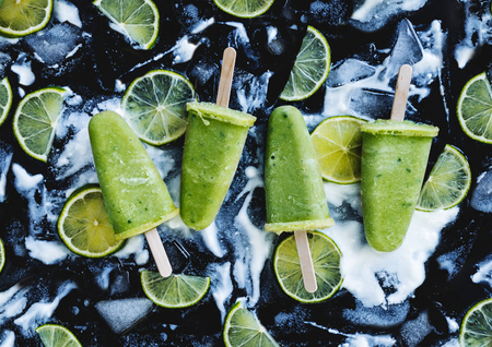 Mojito, yogurt and lime popsicles on ice cubes over black background. Refreshing and Healthy summer dessertの写真素材