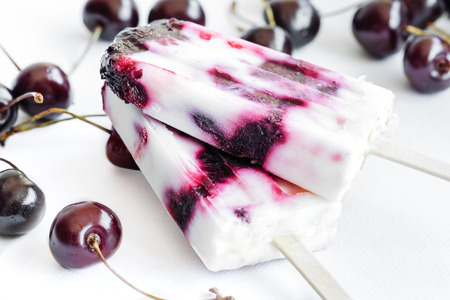 Yogurt and cherries popsicles on white background. Refreshing summer dessert.の写真素材