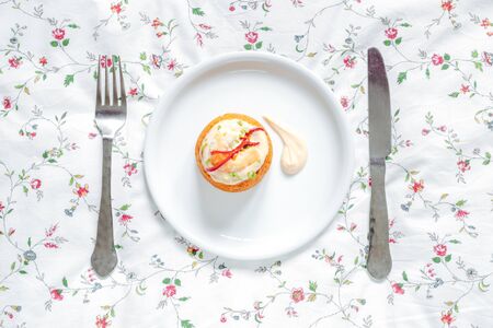 Traditional fish cake. Hake cake with tomato, shrimps and salad cream on Flower table cloth. Top viewの写真素材