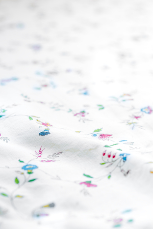 Close up of wrinkled white color fabric and floral bed sheet texture background.の写真素材
