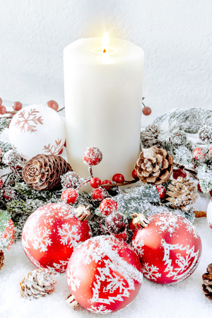 Christmas decorations. White burning candle with red baubles の写真素材