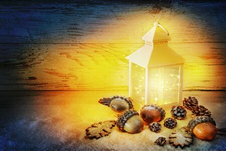 Xmas time. Christmas Lantern On Snow with acorns and oak leaves In Evening Scene.の写真素材
