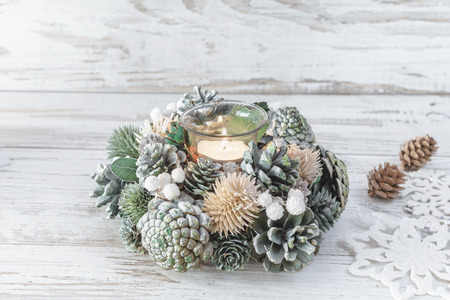 Christmas decoration with candle and snowy fir branches over white wooden backgroundの写真素材