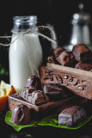 Milk in glass jar with orange and chocolate sweets. Dark wall at background, selective focus, copy space.の写真素材