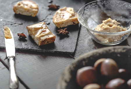 Sweet Chestnut Cream toasts with rosemary honey and anise stars. Rustic wooden background. Selective...