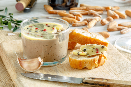 Chicken liver pate jar covered with melted butter and decorated with bay leaves and black and red pepper.の写真素材