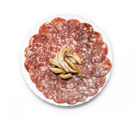 Traditional Iberian Salami Sausage dish (Salchichon Iberico) with breadsticks isolated on white background. Iberian salchichon. Iberian pork meat. Top view.の写真素材
