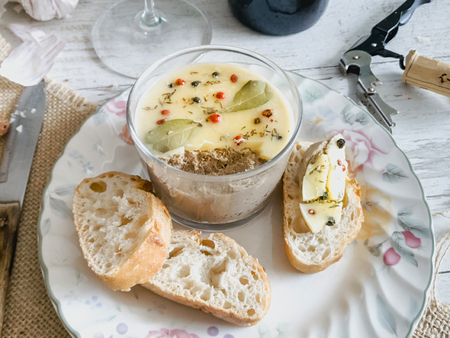 Chicken liver pate covered with melted butter and decorated with bay leaves and black and red pepper...
