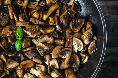 Delicious and healthy fried Mushroom champignon with olive oil, onion, garli, chilli and basil on rustic table.の写真素材