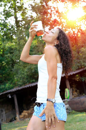 Happy young woman drinking cold drink and having fun outside at forest. Summer conceptの写真素材