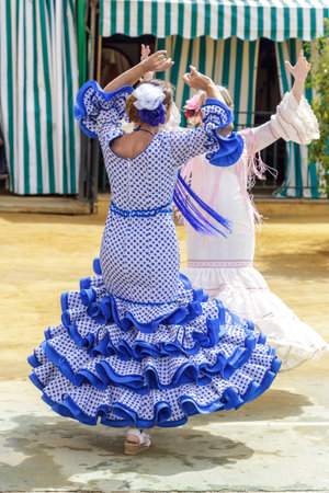 Seville, Spain - May 04, 2017:  Women dressed in colourful flamenco dresses and dancing at the Seville April Fair. The Feria de Abril has a history that dates back to 1857 and takes place a fortnight after Easter each year. The origin of the fair was a caのeditorial素材