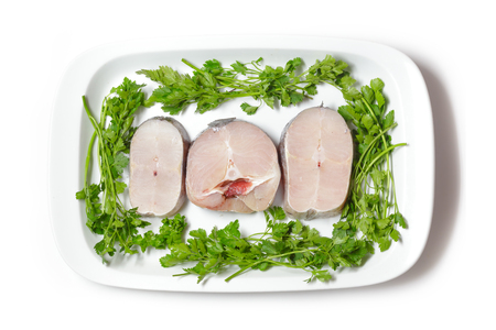 Pieces of fresh raw hake with parsley isolated on white background.の写真素材
