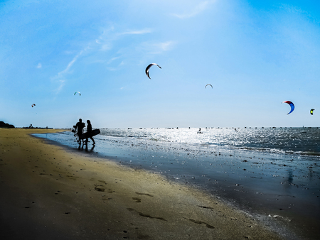 Silhouette Of kite surfers carrying their boards on the ocean beach. Outdoor Active Lifestyle. Holidays on nature. Water sports, hobbies and fun in summer.の写真素材