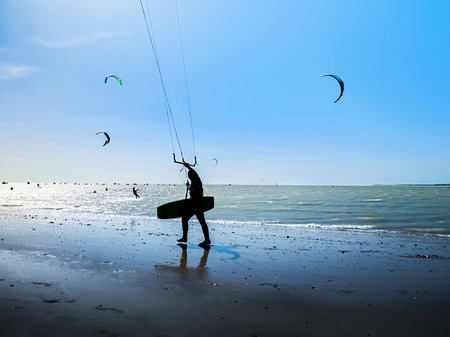 Kite surfer on the ocean beach. Silhouette of kite surfer across the sea shore.の写真素材