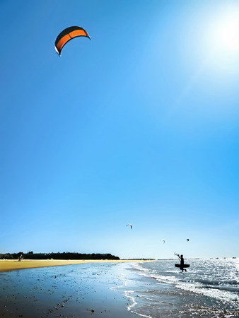 Kite Surfer walking out the sea against a beautiful blue sky. Silhouette of kite surfer in the beach. Holidays on nature. water sports, hobbies and fun in summer. の写真素材