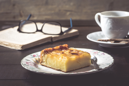 Sweet homemade apple cake and coffee. Breakfast and reading on rustic wooden table.の写真素材